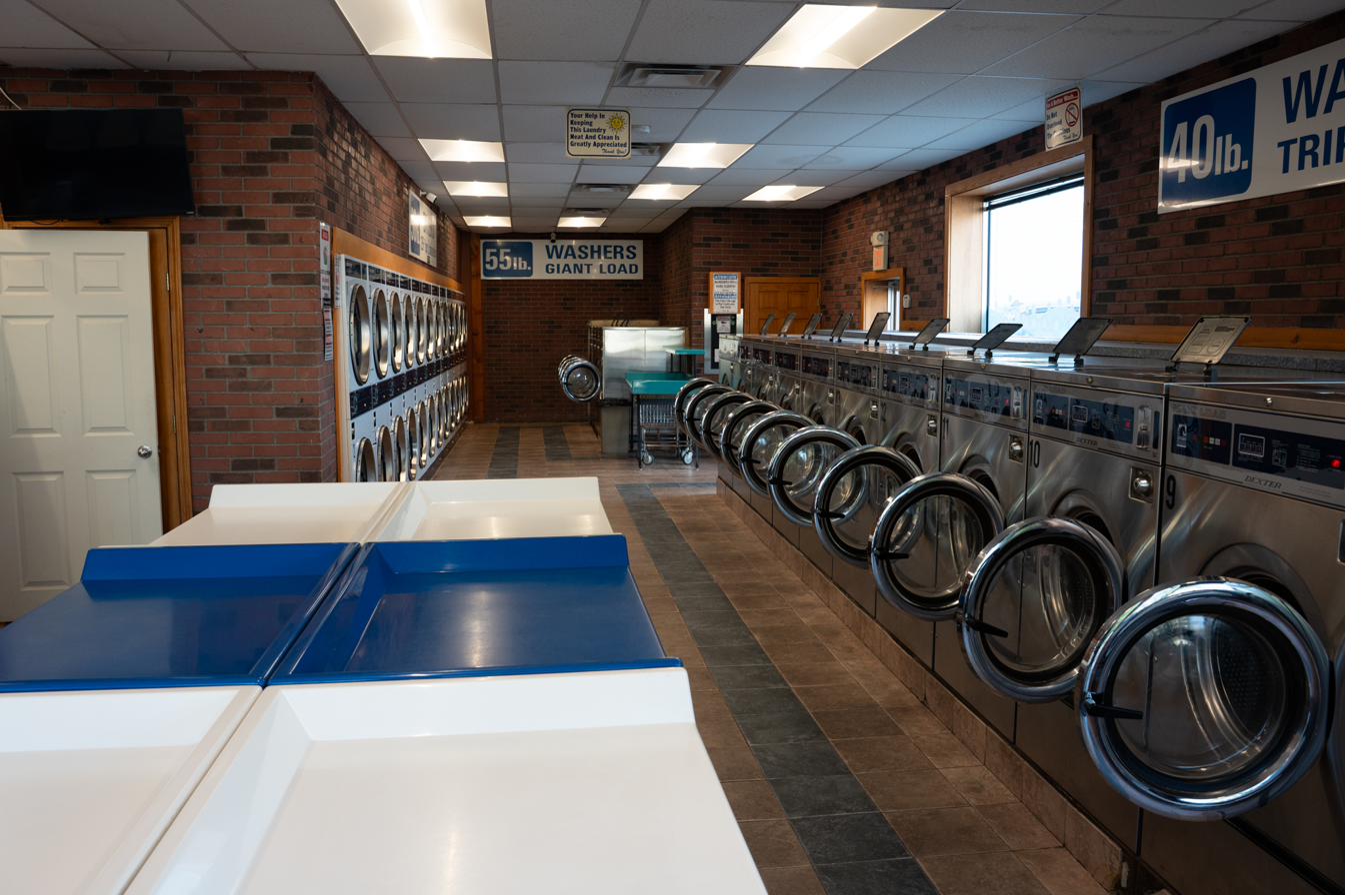 Inside Highland Laundromat — clean tile floor, sorting tables, and rows of washers